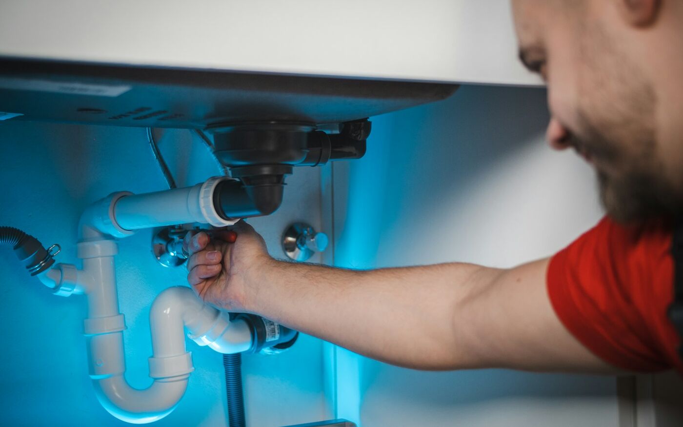 Plumber repairing the pipes under a kitchen sink