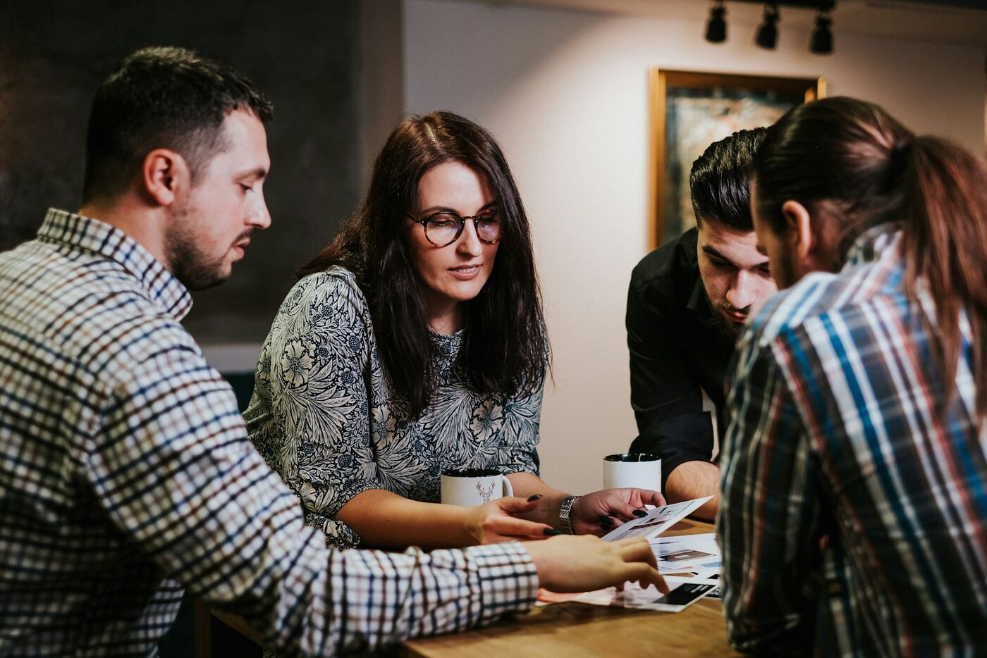 A small marketing team gathered around a table reviewing printed ad creative together